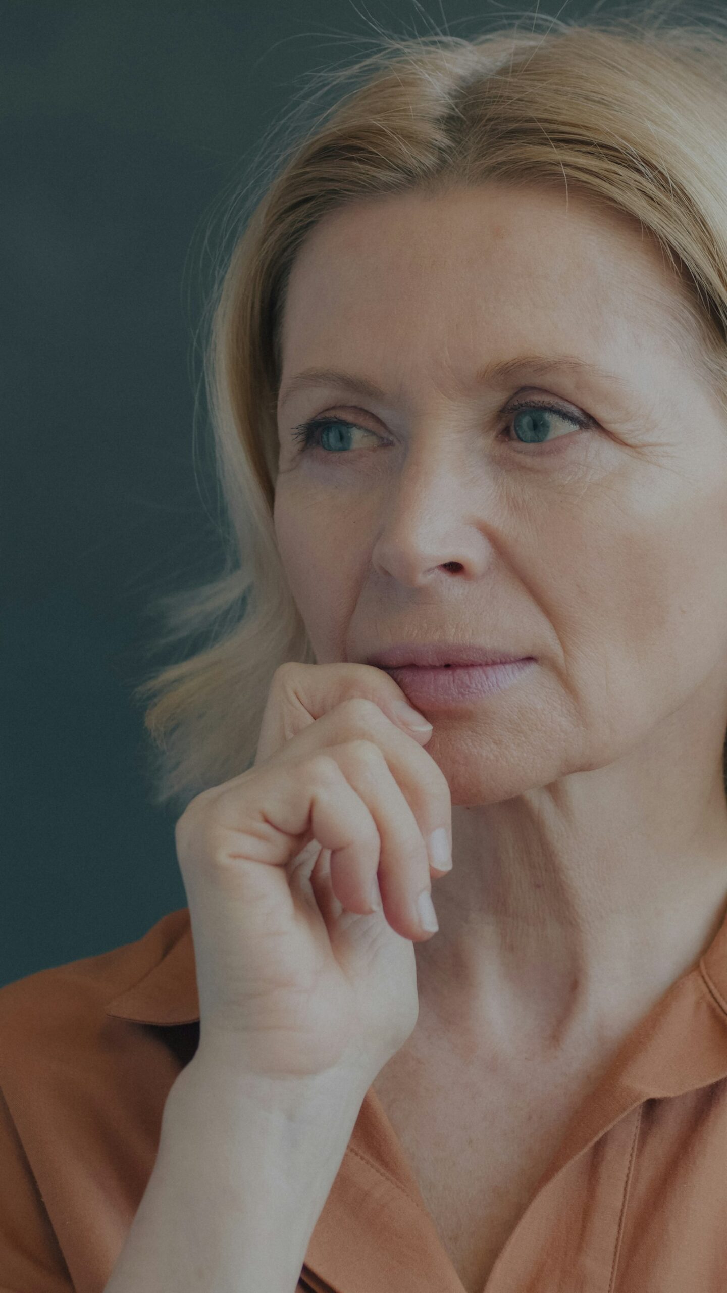 Mature woman with natural skin resting her chin on her hand