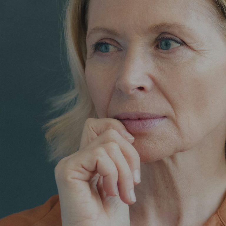 Mature woman with natural skin resting her chin on her hand
